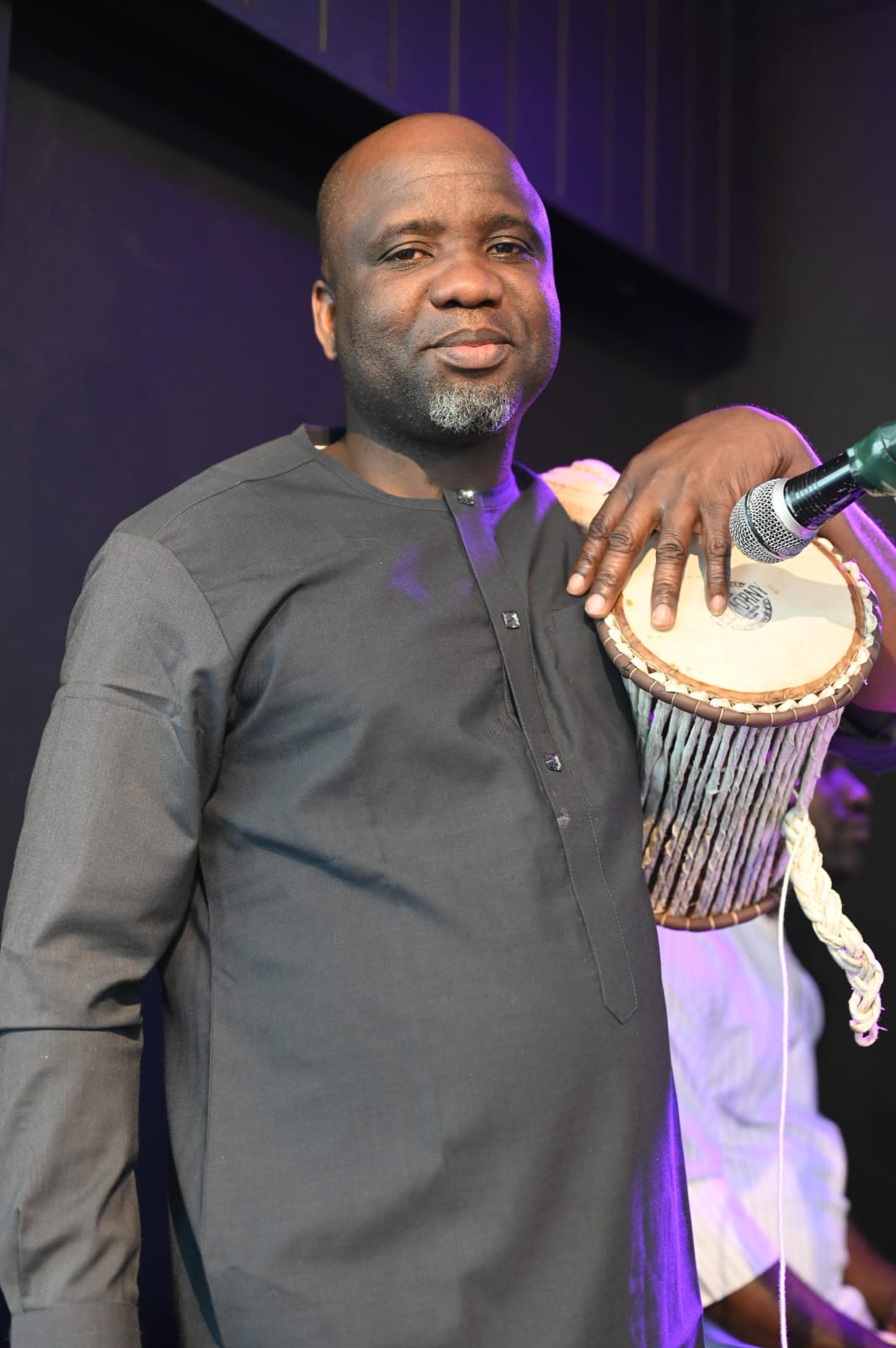 Sunday Abidemi Ipadeola holding a talking drum on stage